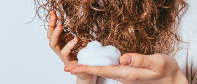 A woman applying mousse to her damp hair
