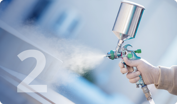 A hand holding an air sprayer with coatings being released