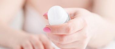 A woman holding a roll-on deodorant stick