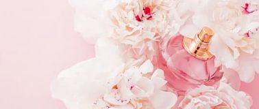 img title Fragrance bottle in bunch of flowers on pink background