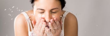 Woman washing her face with water